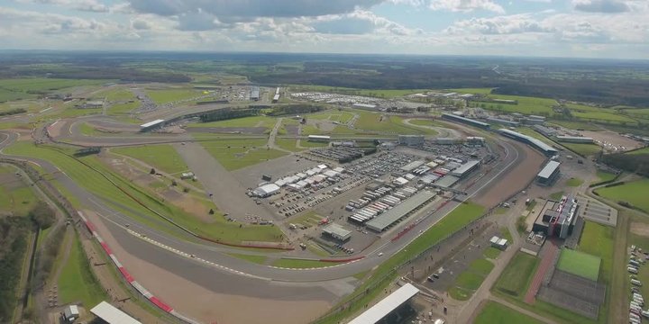 Aerial view of a big race on a sunny summer day in England. Cars going along the race. Full campsite.