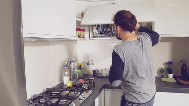 Man dancing while preparing coffee in kitchen in pajamas