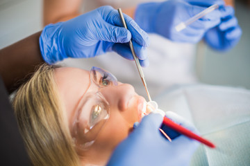 Close-up patient of stomatology clinic whom dantist treats teeth with the help of dental instruments, indoors