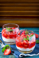 Air dessert with strawberries, mascarpone and strawberry jelly in glasses on a vintage blue background. Place for your text.