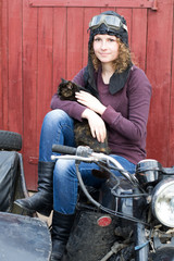 Fototapeta na wymiar Photo of girl on a vintage motorbike in pilot cap with cat