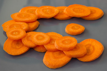 Bright round pieces of raw carrots on a gray background. Horizontal.