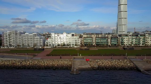 Amazing aerial view of the Malmo Western Harbour promenade with beautiful houses and a turning torso skyscraper view during sunset. View from the sea.