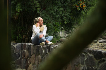 Fototapeta premium Attractive young woman sitting in a cold forest enjoying the view