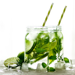 Cold and refreshing detox water with lime, cucumber, rosemary and ice in glass jar. Copyspace