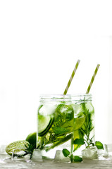 Cold and refreshing detox water with lime, cucumber, rosemary and ice in glass jar. Copyspace