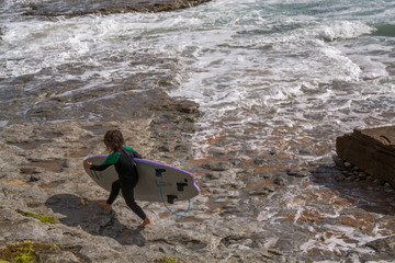 Small Surfer Girl in Ribeira de Ilhas Beach in Ericeira Portugal.