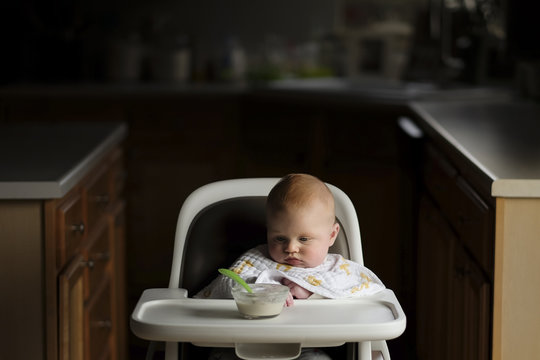 Baby boy looking at food in bowl while sitting on high chair