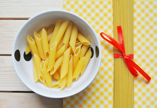 Different types of italian pasta, penne and spaghetti on kitchen table.