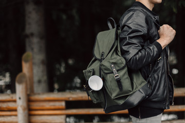 The man in the woods. Male with a black backpack and a mug