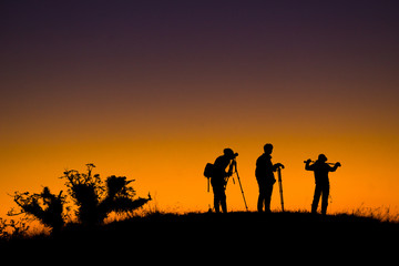 Silhouette of aphotographers top of mountain on sunset.