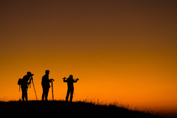 Fototapeta na wymiar Silhouette of aphotographers top of mountain on sunset.