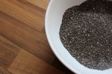 Chia seeds in white bowl with braun background