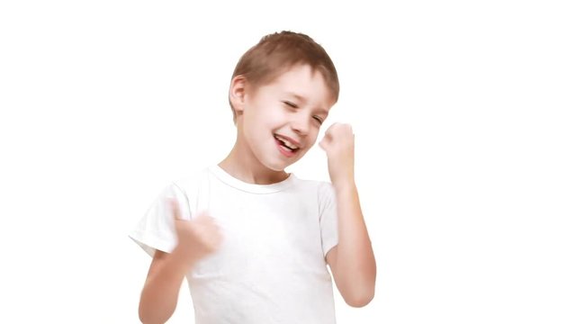 Young Caucasian boy happily moving hands and showing ok at camera with big smile. Footage on white background in slowmotion