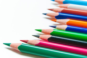 Many different colored pencils on paper background.
