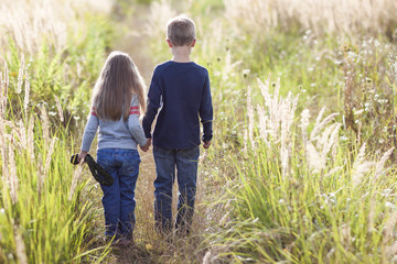 Little boy and little girl standing holding hands looking on horizont. Rear view. © bilanol
