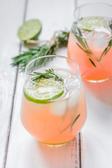 vegetable smoothie with lime and rosemary in glass on white table background