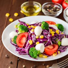 Fresh vegetable salad with mozzarella on wooden table.