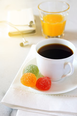 Morning coffee, orange juice, gummy candy and mobile phone. Toned image