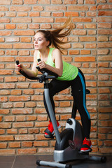 Fototapeta na wymiar Active woman using exercise bike at the gym.
