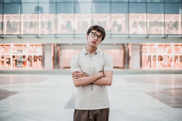 Young asian boy posing on the street without technology devices. Wearing a polo and wide pants. Man with arms crossed