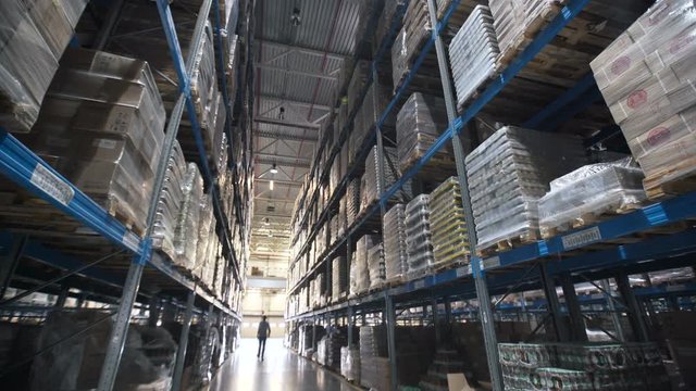 moving between palettes with ordered goods and materials at warehouse. Large warehouse logistics terminal. Shot inside Logistic Store