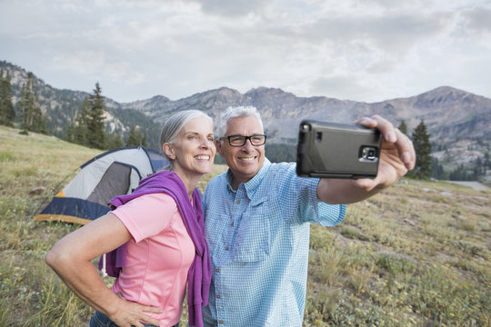Caucasian couple posing for cell phone selfie on mountain