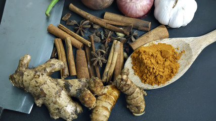 cinnamon, curry powder, garlic, onion, chili, meat cleaver on a black background, Concept cuisine Asian countries.