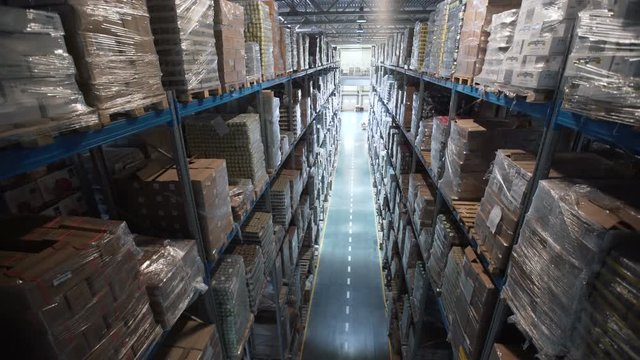 Camera moves up on shelves of cardboard boxes inside a storage warehouse. Large warehouse logistics terminal. Industrial warehouse with boxes