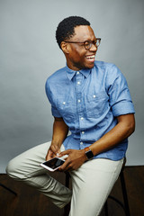 attractive young black male studio holding smart phone laughing at left
