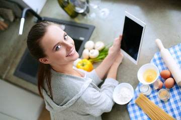 Woman baking at home following recipe on a tablet