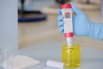 The scientist work at the chemical solution with handle pH meter