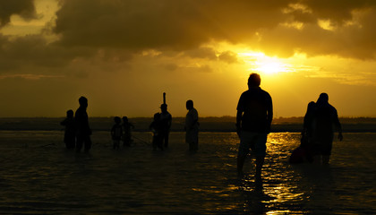 silhouette of people, sunset view from a beach, visitors seem to enjoy the beach at sunset,