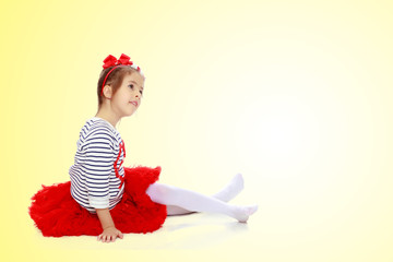 Little girl in a red skirt and bow on her head.