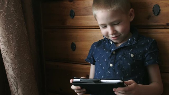 A child with a tablet, watching cartoons, smiling