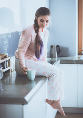 Young woman sitting on table in the kitchen