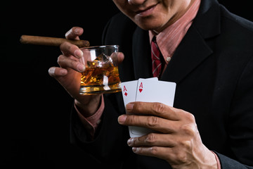 Man holding glass of whiskey with cigarette and show winning in poker games.