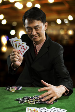 A man wearing a suit holding Hearts Suit Straight Flush