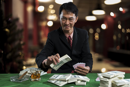 The young gambler is putting bets into the piles of banknote