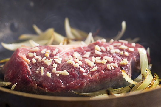 Steak cooking with garlic and onion