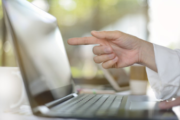 Hand pointing at computer screen in office environment
