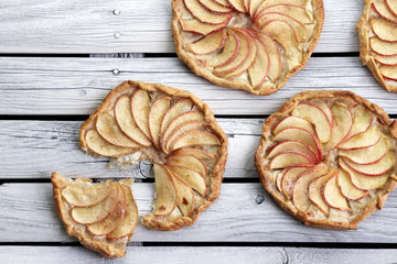 Apple pie on the thin crust with sugar and cinnamon. Apple tart with ricotta cheese and cinnamon. Round pies on the white wooden background. Apple's slices. Piece of pie.