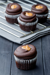 Chocolate muffins with chocolate cream. Chocolate cupcakes filled with almond butter and topped with chocolate mousse. Homemade bakery. Rustic background.