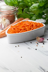 Carrot salad. French Grated Carrot Salad. Shredded carrot with garlic, basil and black pepper on the white rustic background. Vegan food. Vegetarian menu. Spring menu.