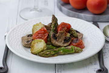 Roasted Vegetables Recipe. Asparagus, Roasted Brussels Sprouts, mushrooms and roasted tomatoes on the white plate. Vegetarian menu. Healthy lifestyle.