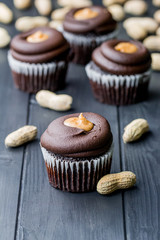 Chocolate cupcakes filled with peanut butter and topped with chocolate mousse. Homemade bakery. Rustic background.