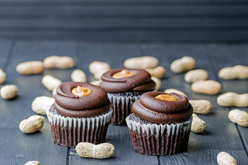 Chocolate cupcakes filled with peanut butter and topped with chocolate mousse. Homemade bakery. Rustic background.