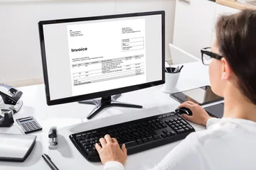 Fotobehang Businesswoman Calculating Invoice On Computer © Andrey Popov