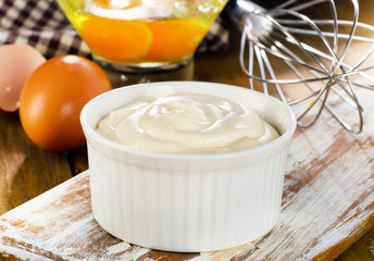 Mayonnaise in  bowl with eggs  on a wooden background