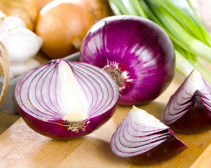 Different fresh onions on  wooden cutting board